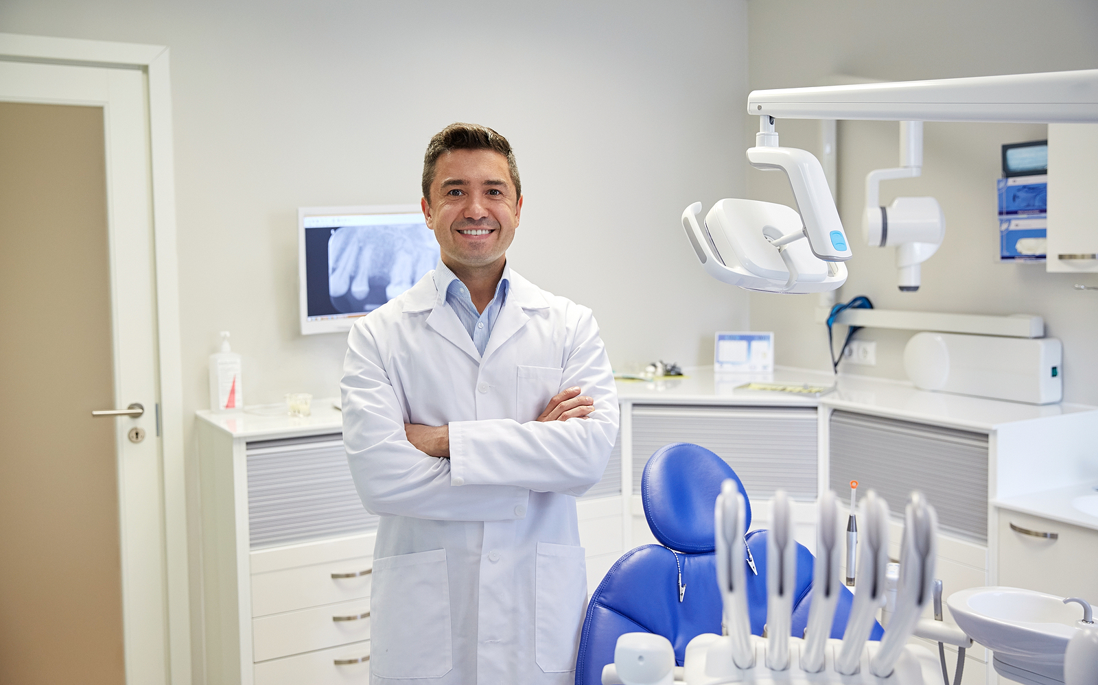 people, medicine, stomatology and healthcare concept – happy mid dentist with arms crossed